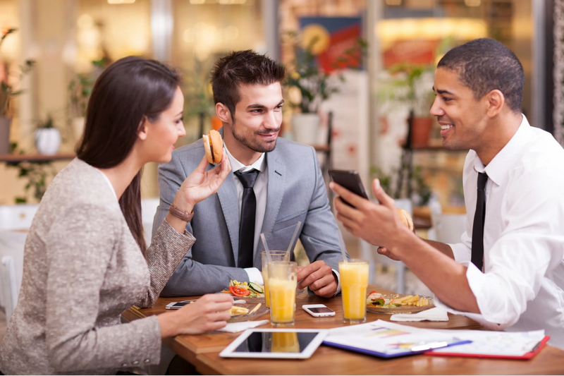 Three people enjoying food and drinks at an outdoor cafe.