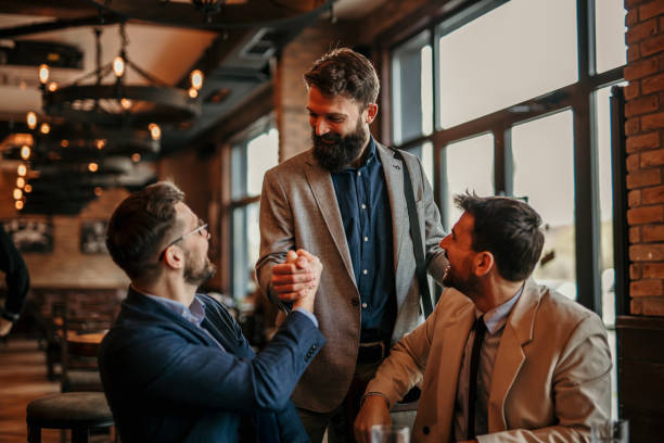 Businessmen shaking hands in a cafe discuss budgeting strategies for an IFZA Free Zone license.