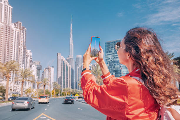 A woman takes a photo of Dubai's skyline, highlighting popular travel spots relevant to UAE entry rules.