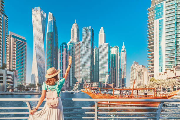 A woman in a hat waves towards Dubai Marina, relating to the list of prohibited goods for import into the UAE.